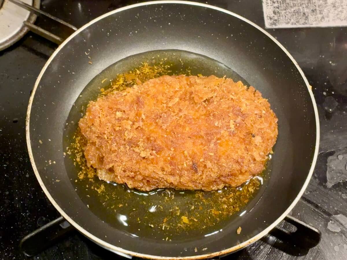フライパンで揚げ焼きしている惣菜のロースカツ